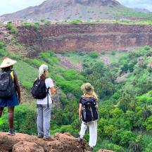 three people standing on a rock looking at a canyon