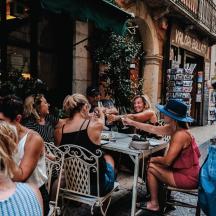 a group of women sitting at a table on a street