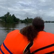 a woman in an orange life vest in a boat on a river