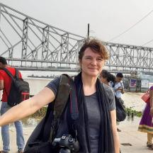 a woman holding a camera in front of a bridge
