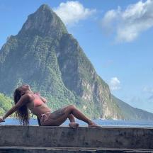 a woman in a bikini sitting on a wall with a skateboard