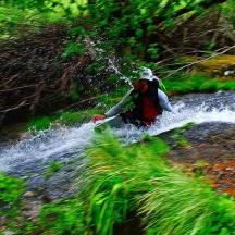 a person is crossing a river with a surfboard