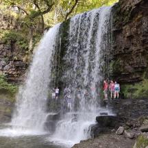 eine Gruppe von Menschen steht vor einem Wasserfall