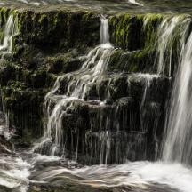 ein Wasserstrahl, der in einem Wasserfall auf Felsen fällt
