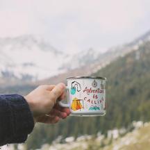 a hand holding a cup with a mountain in the background