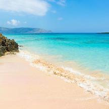 una platja de sorra amb aigües blaves i roques
