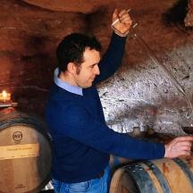 a man holding a glass of wine in a barrel
