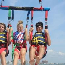 Tre personer kører på en zipline på stranden