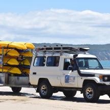 a white truck parked on the beach with yellow objects