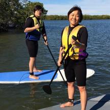 two women standing on a paddle board in the water