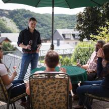 een groep mensen die rond een tafel op een terras zitten