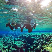 two people are swimming in a coral reef