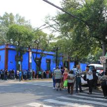 un grup de persones caminant per un carrer amb un edifici blau