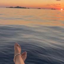 eine Person, die auf dem Wasser sitzt und den Sonnenuntergang beobachtet