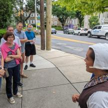 a group of people standing on a sidewalk near a street