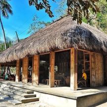a hut with a straw roof with a person sitting in it