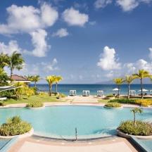 a resort swimming pool with the ocean in the background