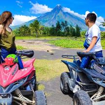 two people riding on atvs with a mountain in the background