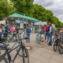 un gruppo di persone in piedi davanti a uno stand di cibo con le biciclette