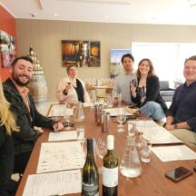 a group of people sitting around a table with wine bottles