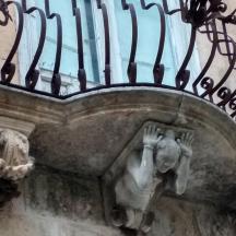 en statue af en person under en balkon