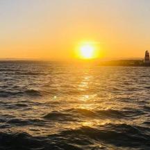 a sunset over a body of water with a lighthouse
