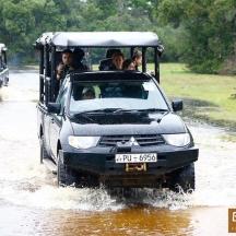 a group of people in a jeep driving through a water logged road