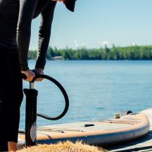 una persona que sosté un paraigua al costat d'una taula de paddle surf