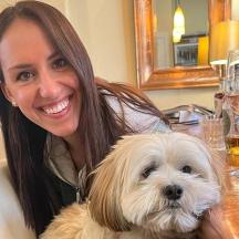 una dona asseguda a una taula amb un gos blanc