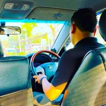 a man driving a car with a surfboard on the dashboard