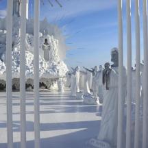 a white gate with a group of statues behind it