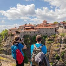 two people standing on a mountain taking a picture of a town