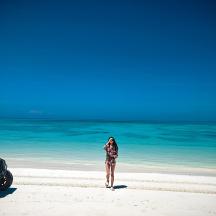 a woman in a bathing suit standing on a beach next to an atv