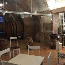 a room with a table and chairs and wine barrels
