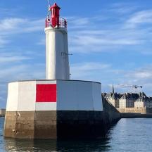 un phare posé dans l'eau à côté d'un bâtiment