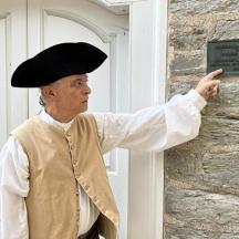a man wearing a hat pointing at a sign
