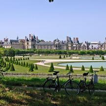 two bikes parked in a park in front of a palace