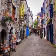an alley with buildings and people walking down a street