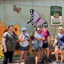a group of women standing in front of a building with butterflies