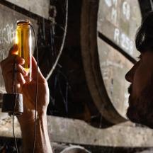 ein Mann hält eine Flasche vor einer Wand