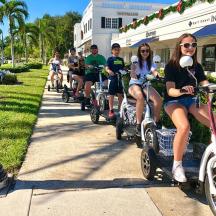 a group of people riding scooters down a sidewalk