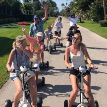 a group of people riding on scooters down a sidewalk