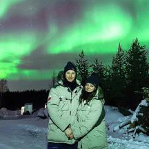 un homme et une femme debout sous les aurores boréales