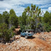 a blue jeep driving down a dirt road