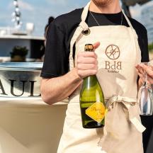 a man in an apron holding a bottle of wine