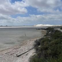 una platja buida amb sorra i neu a l'horitzó