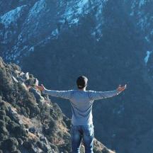 a man standing on top of a mountain with his arms outstretched