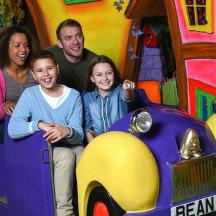 eine Familie sitzt in einem Spielzeugauto und fährt