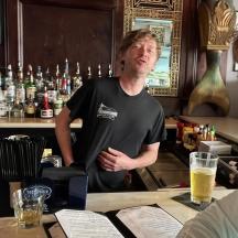 a man standing behind a bar with a woman