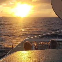 a group of people sitting on a boat watching the sunset